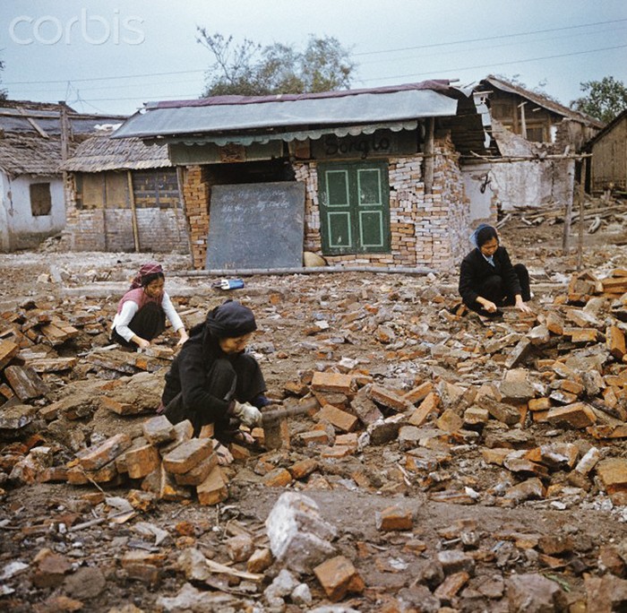 Những người phụ nữ này dùng dao tách những mảng xi măng trên gạch từ những ngôi nhà bị phá hủy sau đợt công kích của Mỹ tháng 12/1972 tại khu phố Khâm Thiên. Những viên gạch này sau đó sẽ được dùng lại cho việc xây những ngôi nhà mới. Ảnh. © Werner Schulze-dpa-Corbis.